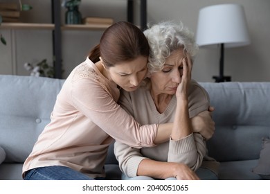 Worried stressed young woman cuddling depressed emotional unhappy middle aged old retired mother, asking forgiveness or supporting in difficult life situation, comforting or soothing at home.