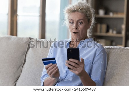 Worried surprised elderly woman holding card, look at smartphone, feels stressed, bad online bank service, overspending, bankruptcy risk, hacked virtual wallet, theft, money steal, crime, e-bank fraud