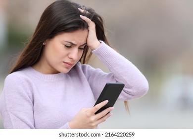 Worried Teen Checking Bad News On Smart Phone In The Street