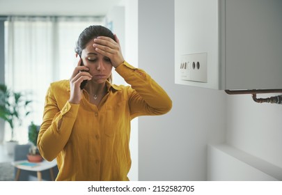 Worried woman calling a boiler breakdown emergency service using her smartphone - Shutterstock ID 2152582705