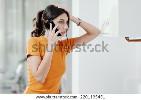 Worried woman calling a boiler breakdown service at home, her boiler is not working