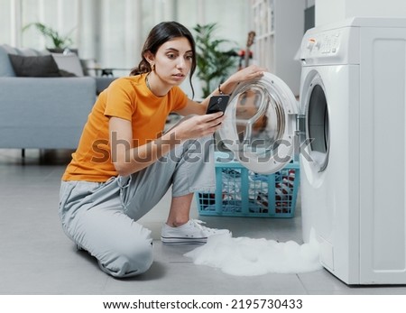 Worried woman calling a repairman, the washing machine is broken