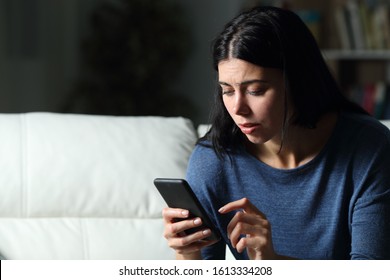 Worried Woman Checking Cell Phone Text Sitting On A Couch In The Night At Home In The Night