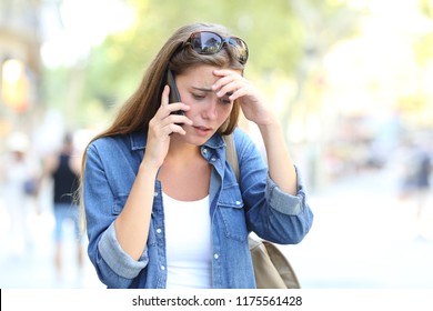 Worried Woman Having A Mobile Phone Conversation Walking In The Street