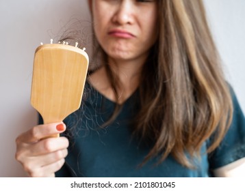 Worried woman holding comb with hair loss after brushing her hair. Hair loss it cause from family history, hormonal changes, unhealthy of aging.