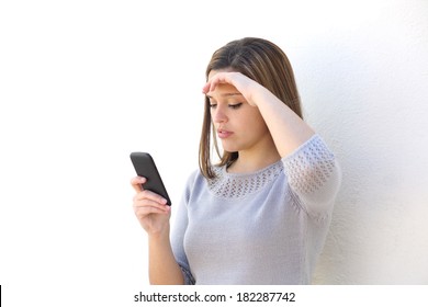 Worried Woman Looking At The Mobile Phone On A White Wall Isolated          