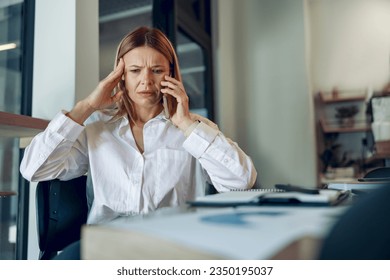 Worried woman manager makes business call and listens client claim while sitting in modern office - Powered by Shutterstock