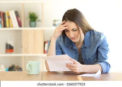 Worried Woman Reading Bad News In A Letter On A Table At Home