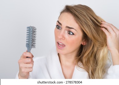 Worried Woman Suffering From Hairloss Looking At Comb