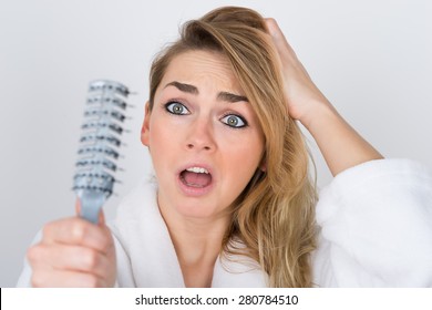 Worried Woman Suffering From Hairloss Looking At Comb