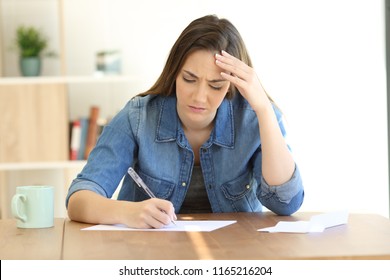 Worried Woman Writing A Letter On A Table At Home