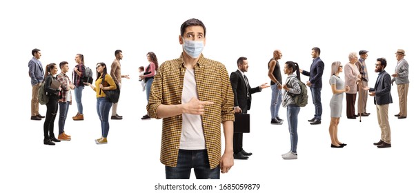 Worried Youn Man With A Medical Face Mask Pointing To A Large Group Of People Talking Isolated On White Background