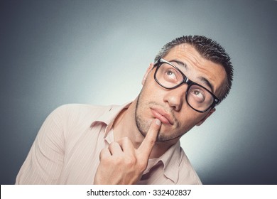 Worried young businessman looking up. Confused man with eyewear thinking