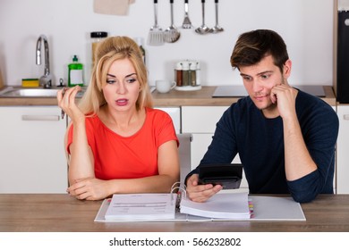 Worried Young Couple Calculating Their Bills In The Kitchen At Home