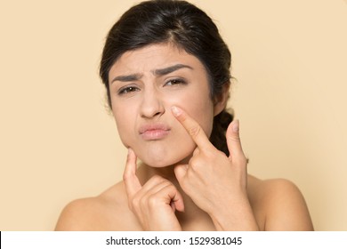 Worried Young Ethnic Woman Isolated On Orange Brown Studio Background Look At Camera Squeeze Pimple, Stressed Unhappy Indian Girl Touch Face Anxious About Wrinkle, Cosmetology, Skincare Concept