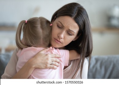 Worried Young Foster Care Parent Mother Comforting Solacing Embrace Adopted Little Child Daughter Give Care And Protection At Home, Loving Concerned Adult Mom Hug Sad Small Girl Consoling Kid Concept