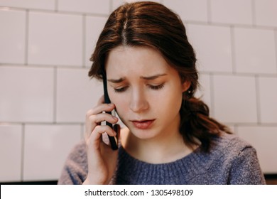 Worried Young Girl Is Talking On The Phone. She Looks Very Unhappy.