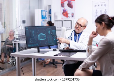 Worried young lady during consulation sitting in clinic room talking with senior doctor, looking at computer analysing body and brain functions, medical consultation in hospital private clinic. - Shutterstock ID 1899201736