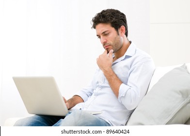 Worried Young Man Looking At His Laptop Computer With Pensive Expression