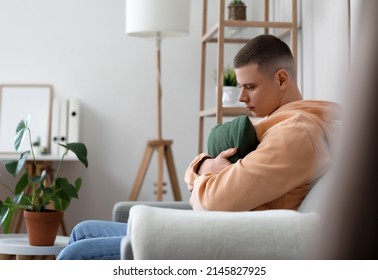 Worried Young Man With Pillow Sitting On Sofa At Home