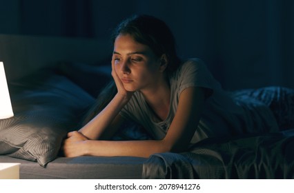 Worried young woman lying on bed at night, she is thinking and she is unable to sleep - Powered by Shutterstock