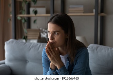 Worried young woman sit on sofa look aside lean forward with folded hands feel fear anxiety. Teen female stressed with unwanted pregnancy thinking on abortion hesitate have doubts making hard decision - Shutterstock ID 1916666765