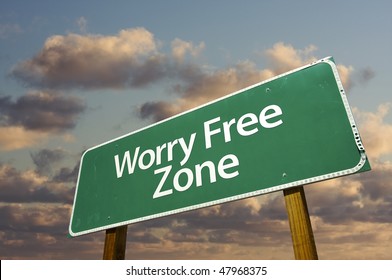 Worry Free Zone Green Road Sign In Front Of Dramatic Clouds And Sky.