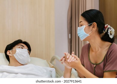 Worrying Asian Mother Holding Hand And Take Care Patient Teenager Son Wearing Protective Face Mask After Recovery From Covid Quarantine Treatment In Hospital. Family Love And Medical Treatment.