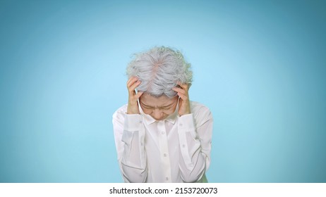 Worrying Asian Senior Woman. Blue Background.