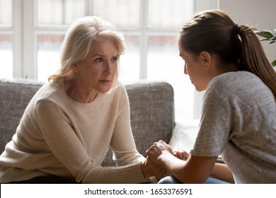 Worrying middle aged retired carrying woman sitting opposite young adult daughter, holding hands, listening to relations or health problems, showing support, giving advices, talking heart-to-heart. - Powered by Shutterstock