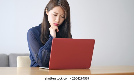 Worrying young Asian woman using a laptop PC.