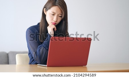 Worrying young Asian woman using a laptop PC.