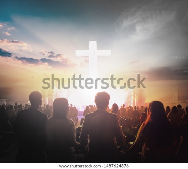 Worship concept: Group of people holding hands\
praying worship at sunset\
background