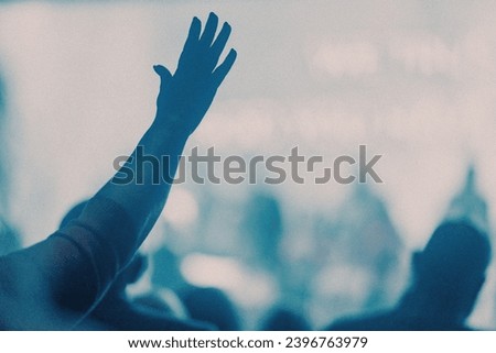 Worshipful hand raised in a bright room - blue light