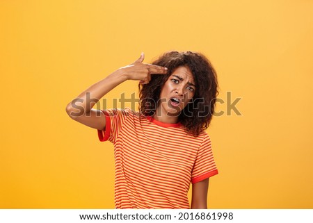 I would rather kill myself. Displeased bored and dissatisfied attractive bothered girlfriend in striped t-shirt tilting head, grimacing from dislike putting finger gun to forehead, commiting suicide