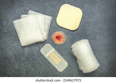 Wound Care Concept: Close-up Of A Fake Wound Surrounded By Different Bandage Material On Black Background