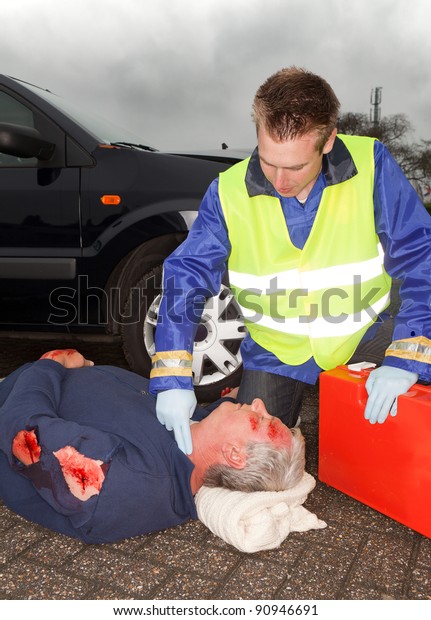 Wounded car\
crash victim being checked by a\
paramedic