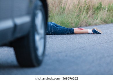 Wounded Legs of a Boy Hit by a Private Car Lying Behind the Vehicle on the Roadway - Shutterstock ID 369696182