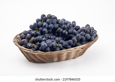 A woven basket of bunches of blue grapes isolated on white