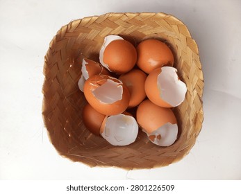 A woven basket filled with eggs and eggshells on a white surface. on top view.