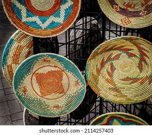 Woven decorative baskets displayed on a metal rack to sell at the market