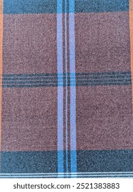 A woven fabric pattern with alternating black and white designs, featuring a repeated diamond-like motif. The design is framed by blue vertical stripes in the center, which adds contrast to the graysc