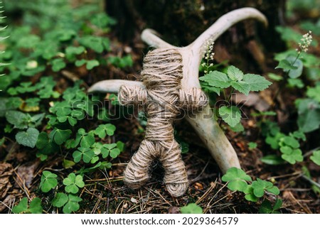 A woven voodoo doll of threads and bones in a ritual in a mysterious forest.