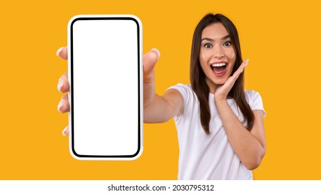 Wow, Amazing Useful App. Portrait of excited and surprised young woman holding smartphone with black blank screen in hand, showing device, closeup. Gadget with empty free space for mock up template - Shutterstock ID 2030795312