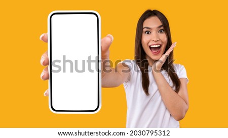 Wow, Amazing Useful App. Portrait of excited and surprised young woman holding smartphone with black blank screen in hand, showing device, closeup. Gadget with empty free space for mock up template