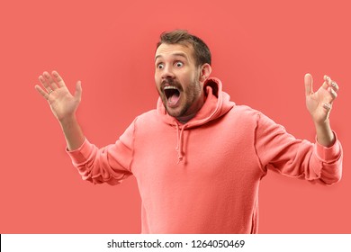 Wow. Attractive Male Half-length Portrait On Coral Studio Backgroud. Young Emotional Surprised Bearded Man Standing With Open Mouth. Human Emotions, Facial Expression Concept. Trendy Colors