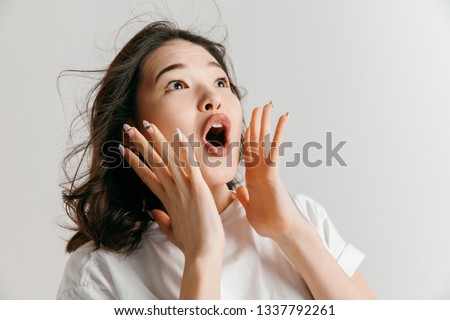Wow. Beautiful female half-length front portrait isolated on gray studio backgroud. Young emotional surprised asian woman standing with open mouth. Human emotions, facial expression concept.