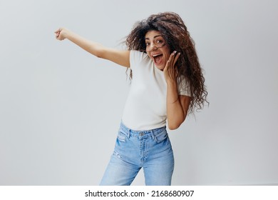 WOW CONCEPT. Shocked Pretty Curly Latin Woman Close Mouth, Look At Camera And Point Finger Up. Autumn Collection, Seasonal Sale Clothing Fashion Brands. Studio Shoot, Copy Space White Background. 