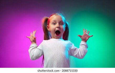 Wow emotions  Studio shot surprised little girl  kid standing and open mouth isolated gradient purple blue color background in neon light  Concept happy childhood  family  love  ad