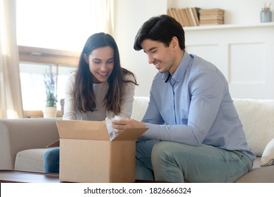 Wow! Excited Curious Millennial Spouses Husband And Wife Opening Unpacking Awaited Parcel With Interest And Pleasure, Glad Happy Young Family Receiving Order Or Delivery From Internet Shop By Mail